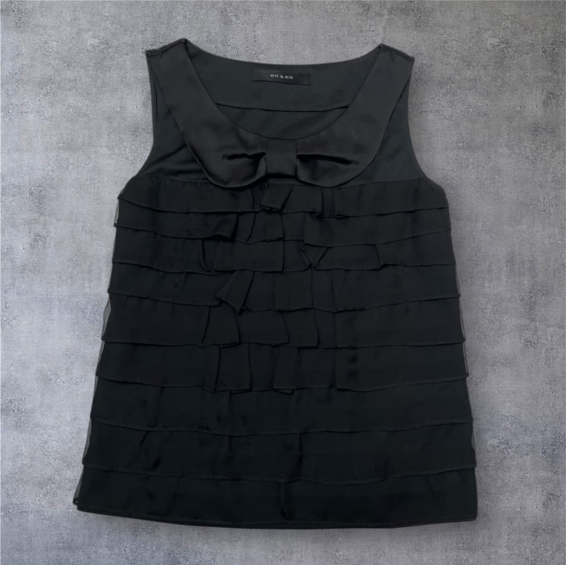 온앤온 On&on 블랙 러플 디테일 리본 카라 슬리브리스 블라우스 55 상품이미지1