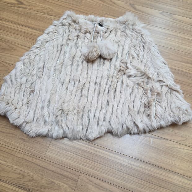 아이보리 색상의 폼폼 케이프 망토입니다. 페이크퍼 소재로 털빠짐 거의 없