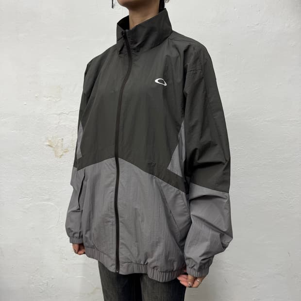 오클리(OAKLEY) 차콜 그레이 컬러블록 테크 하이넥 윈드브레이커