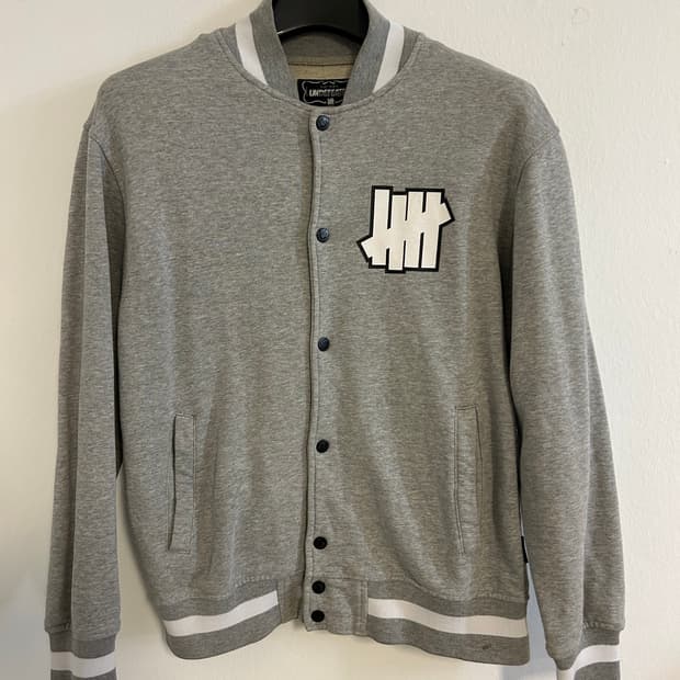 UNDEFEATED 로고 포인트 스냅 바시티 자켓