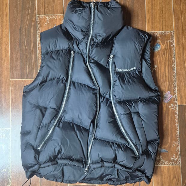 [M]더뮤지엄비지터 커브드 지퍼 패딩조끼